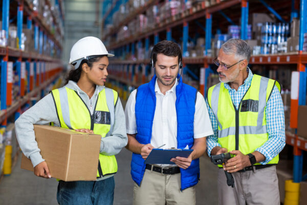 Workers Looking At Digital Tablet In Warehouse